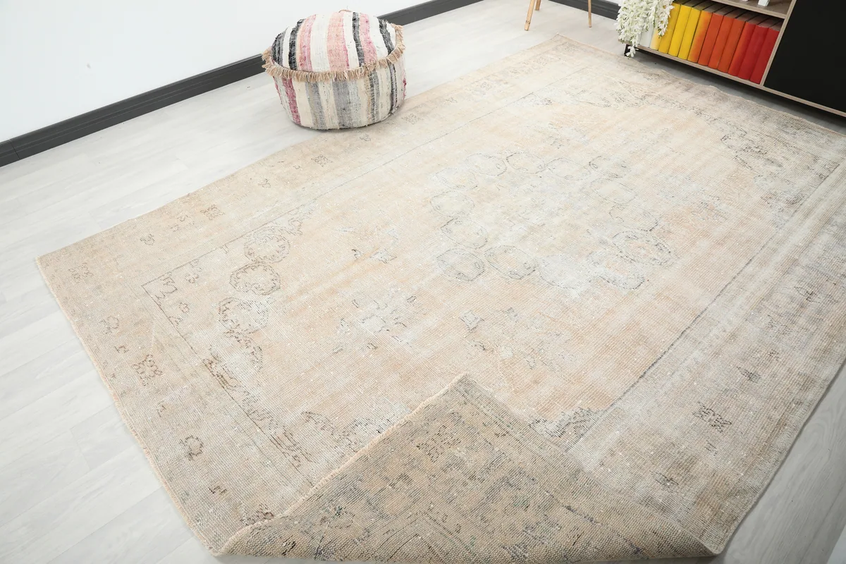 The Beige Medallion Oushak Rug with a corner folded back, showing the cotton foundation.