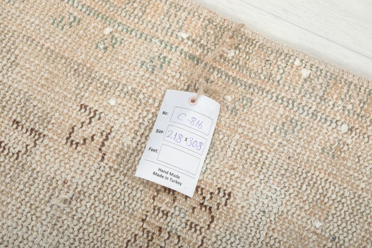 Close-up of the rug's back with a tag showing the dimensions and 'Hand Made in Turkey'.