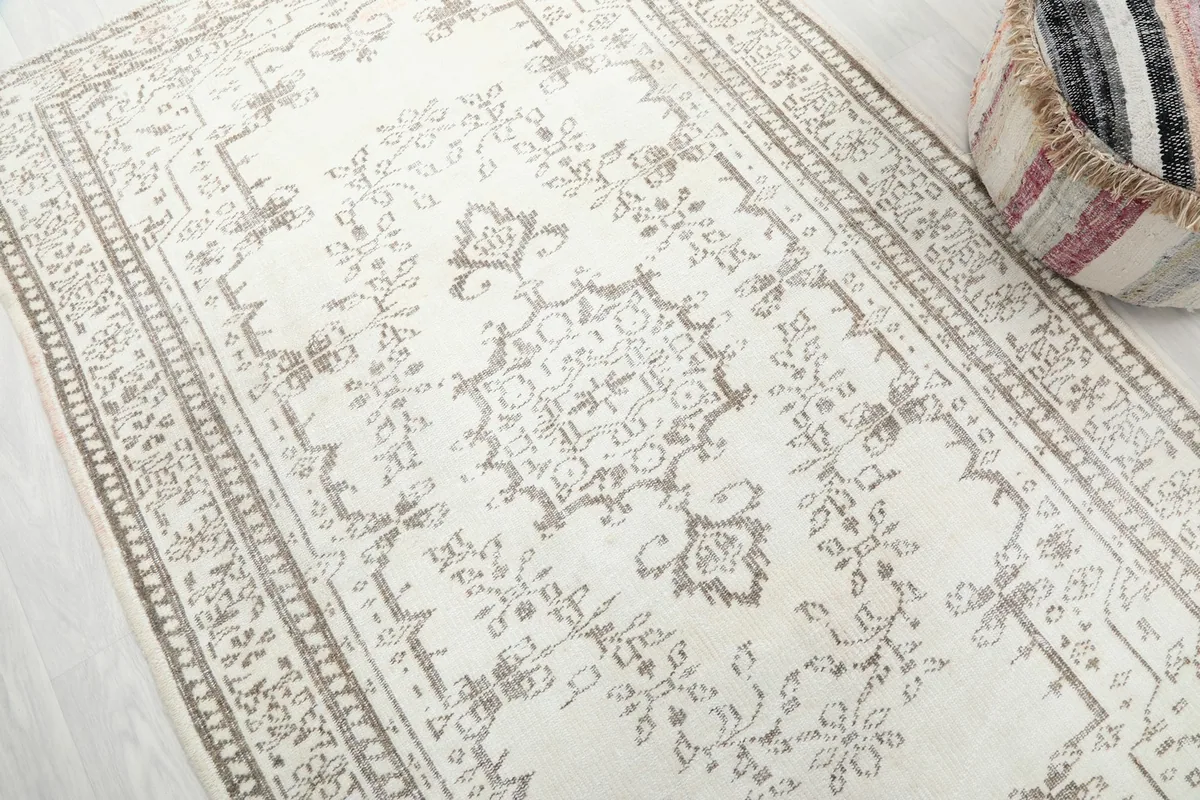 Detailed view of the ivory field and beige geometric medallion motif on the rug