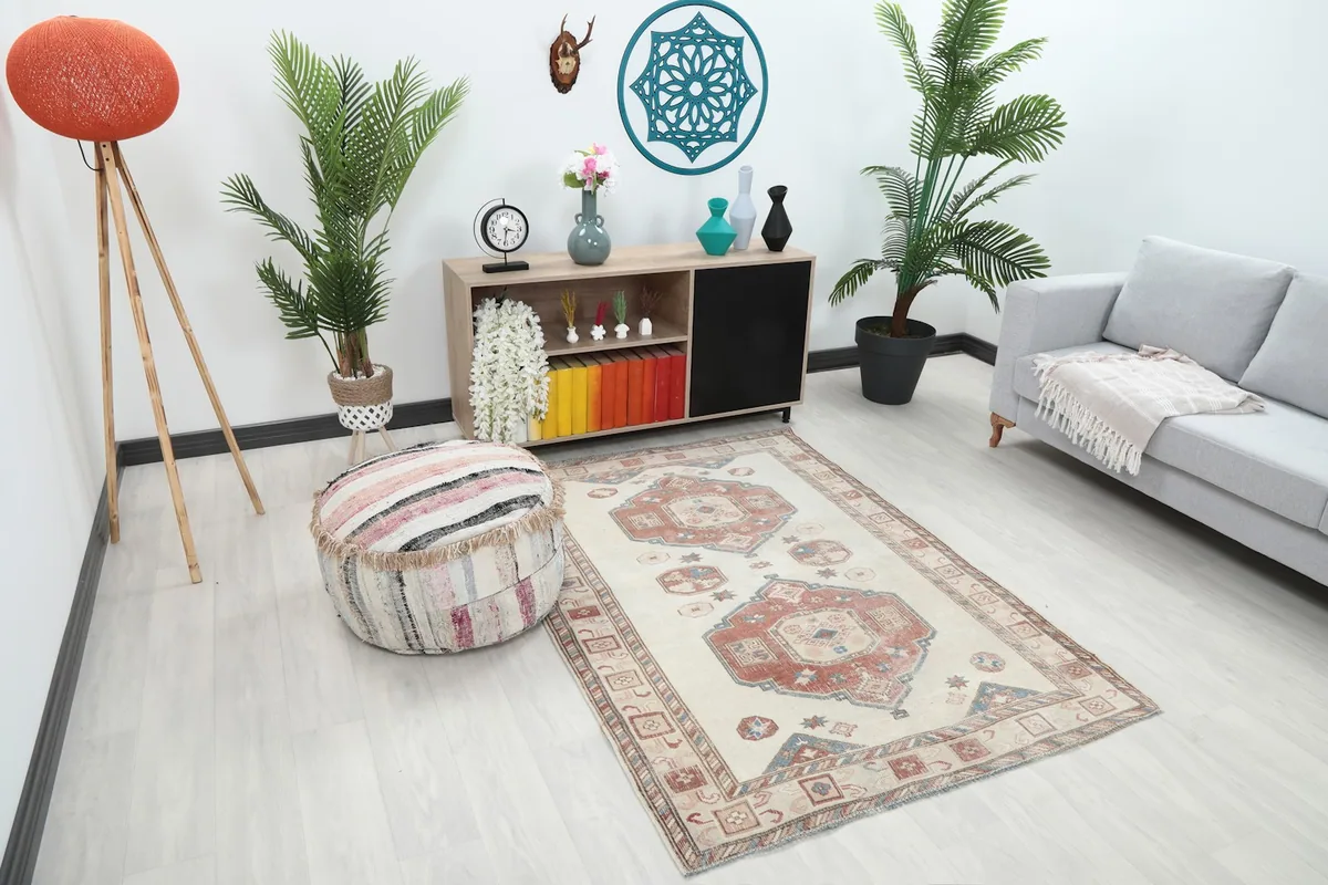 Angle view of the ivory rust geometric vintage rug in a living room setting with a pouf
