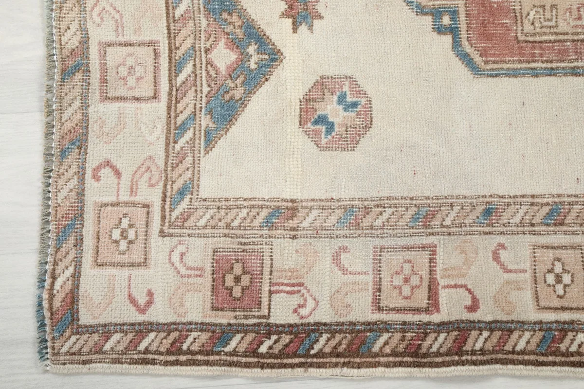 Corner detail of the vintage rug showing the intricate border design and fringe