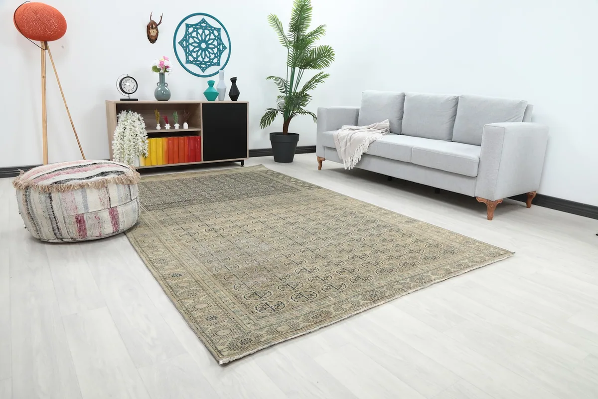 Angle view of the beige and gray area rug in a room with a light gray sofa and a decorative pouf.