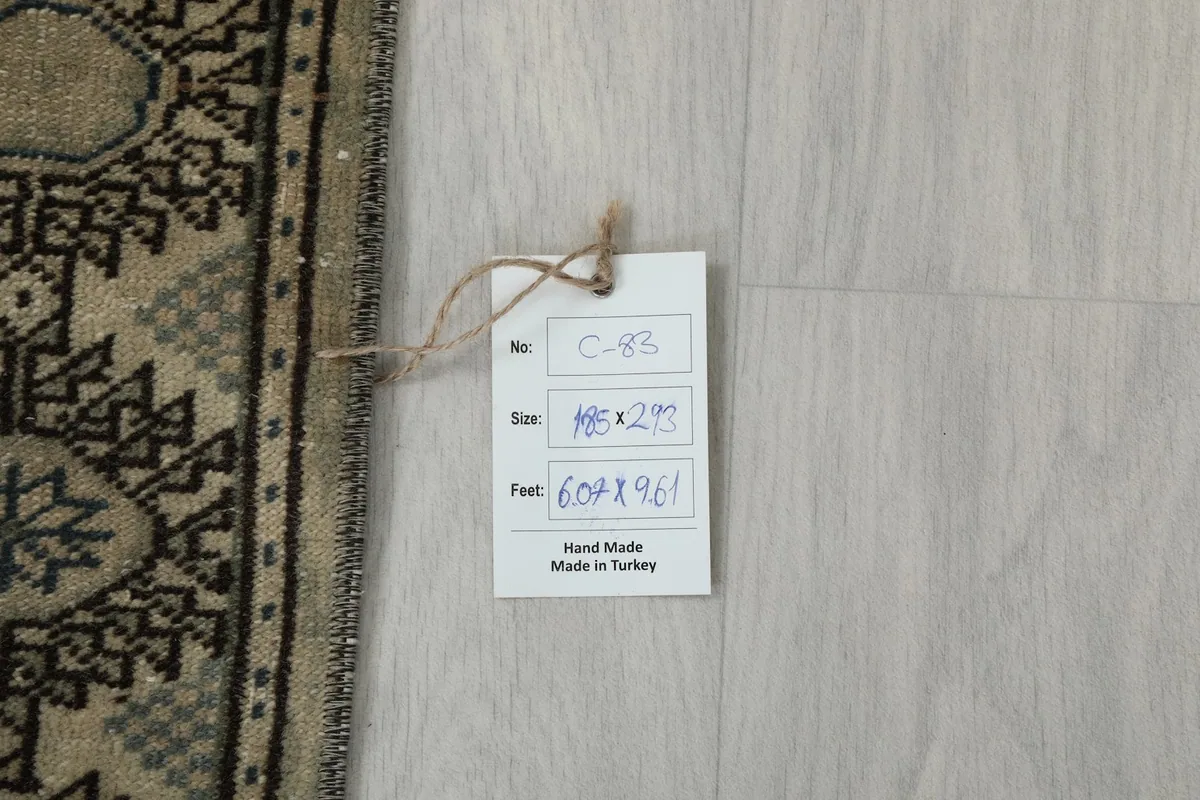 Rug's identification tag with handwritten details, indicating it is handmade in Turkey, next to the rug's edge.