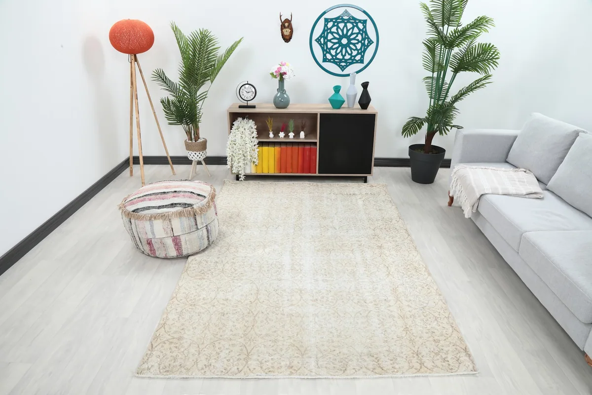 Ivory and beige area rug displayed in a modern living room setting with a sofa and ottoman