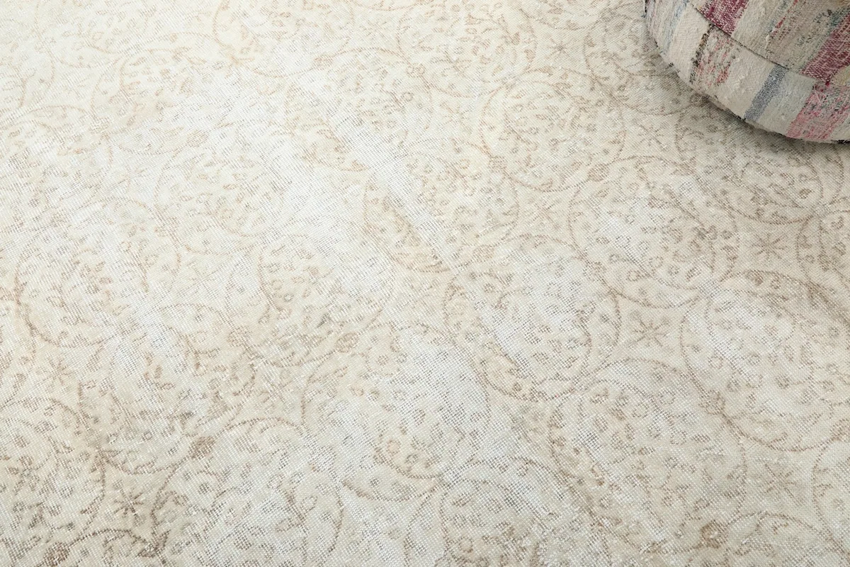 Detailed view of the rug's ivory field and beige floral and medallion motifs