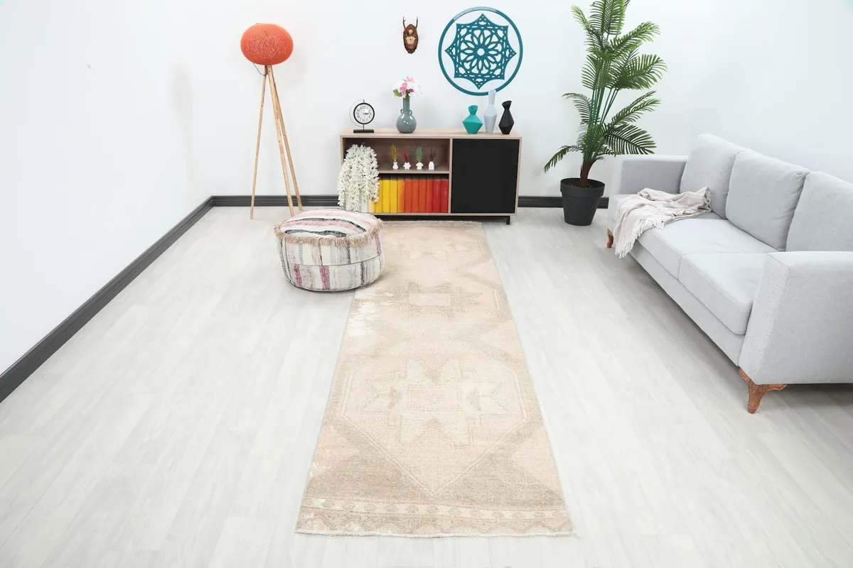 Vintage beige runner rug displayed in a modern living room setting with a sofa and decor.