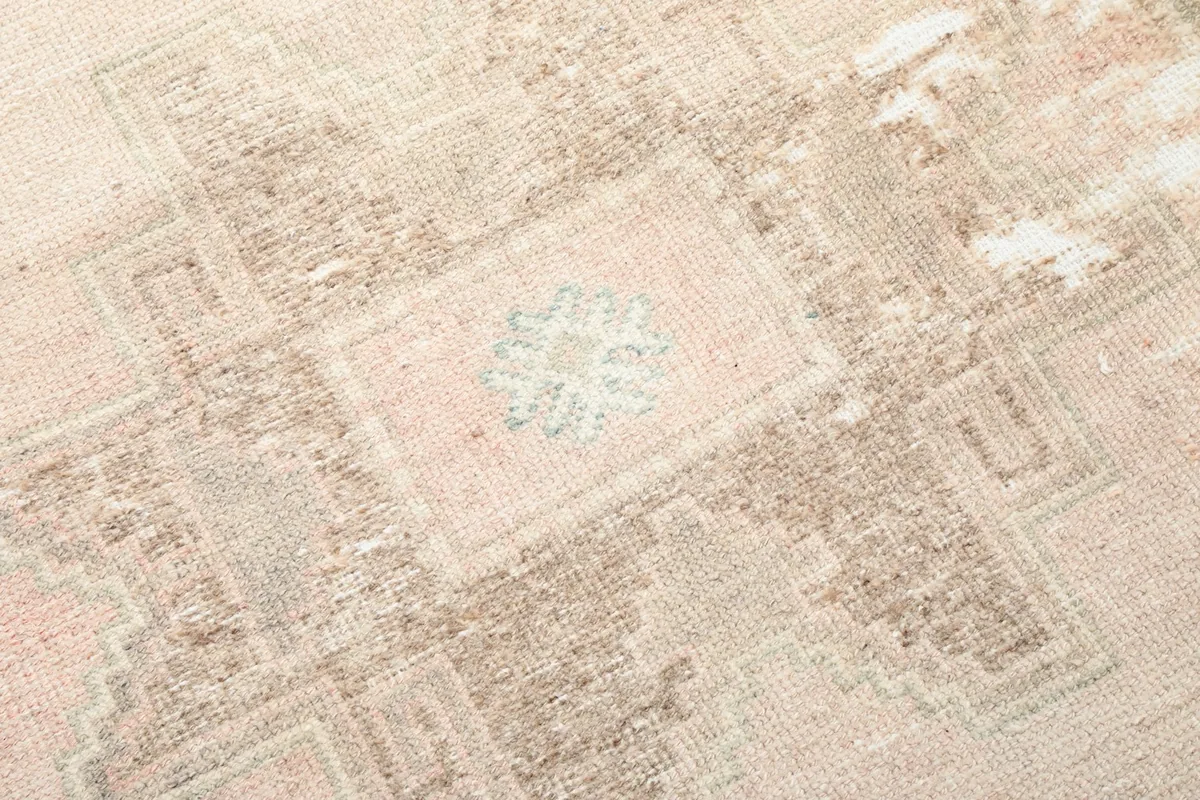 Close-up of a central geometric medallion motif with faint blue and rose accents.