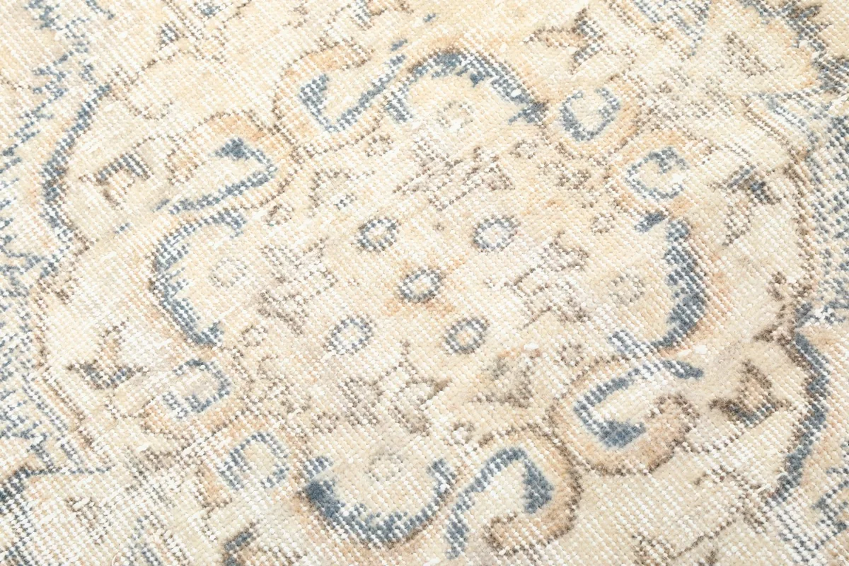 Close-up of the low wool pile texture and faded blue and tan motifs