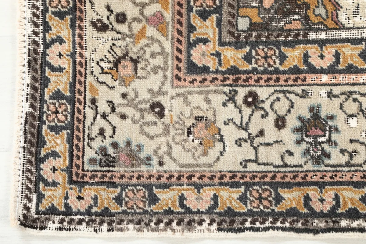 Close-up of the rug's corner and border, showing the ivory background and floral motifs.