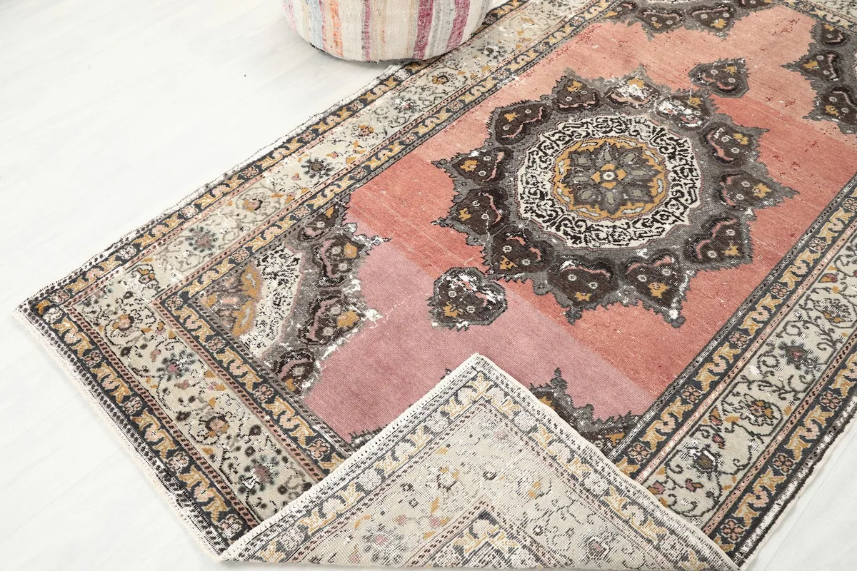 View of the rug with a corner folded back, showing the back of the rug and the front pile.