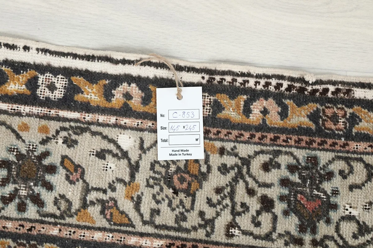 Detail of the rug's border with a product tag, indicating handmade origin.