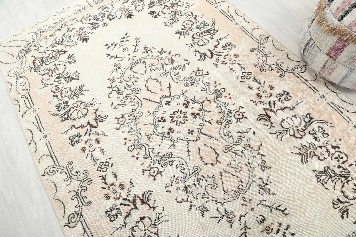 Angled view of the cream rug's surface, capturing the subtle variations in color and texture of the wool pile