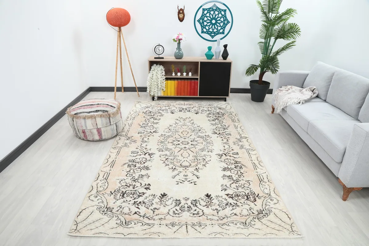 Cream botanical medallion rug placed in a living room setting with a light gray sofa and modern decor