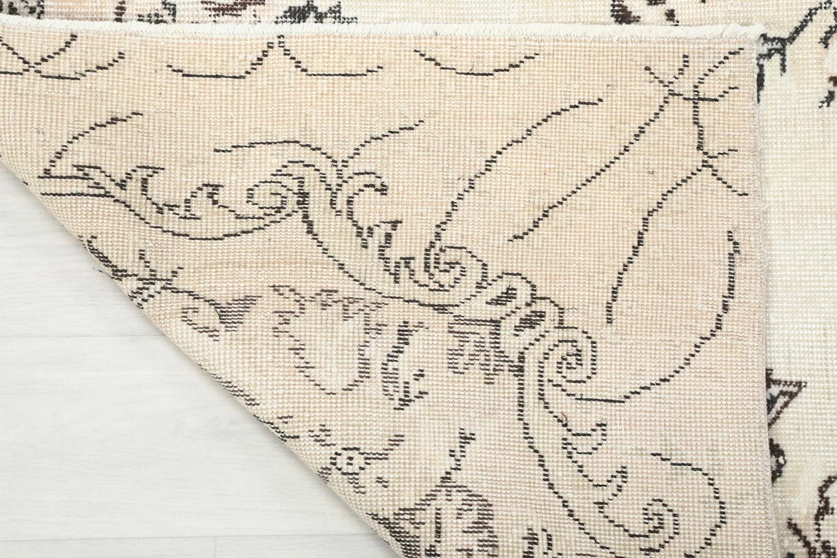 Underside view of the rug's corner, showcasing the tightly woven cotton foundation and knot structure