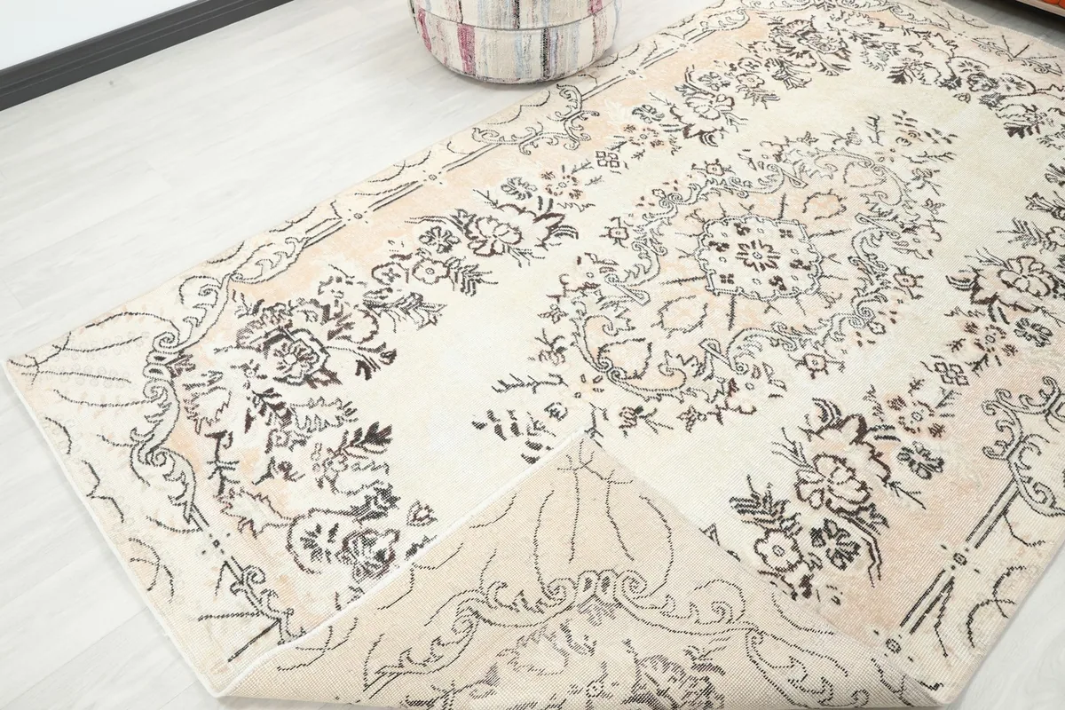 Corner of the cream rug gently folded back, displaying the reverse side of the hand-knotted wool on cotton foundation