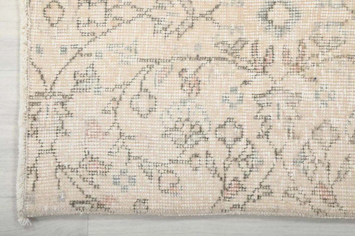 Corner detail of the rug, showing the edge finish and the intricate floral design extending to the border.