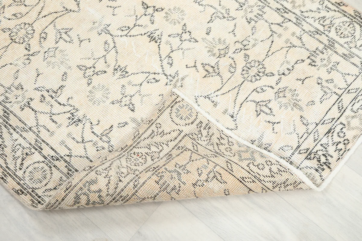 Faded Ivory Floral Anatolian Rug corner folded back, revealing the hand-knotted cotton foundation