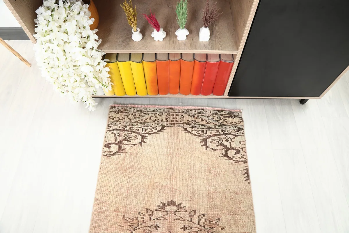 Partial view of the runner rug's end pattern, showing the brown motifs against the beige field.