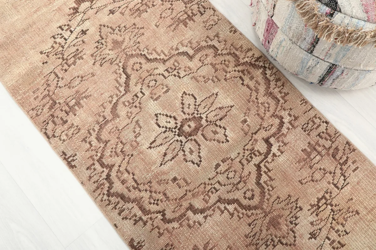 Detailed view of the central medallion pattern on the beige vintage runner rug.