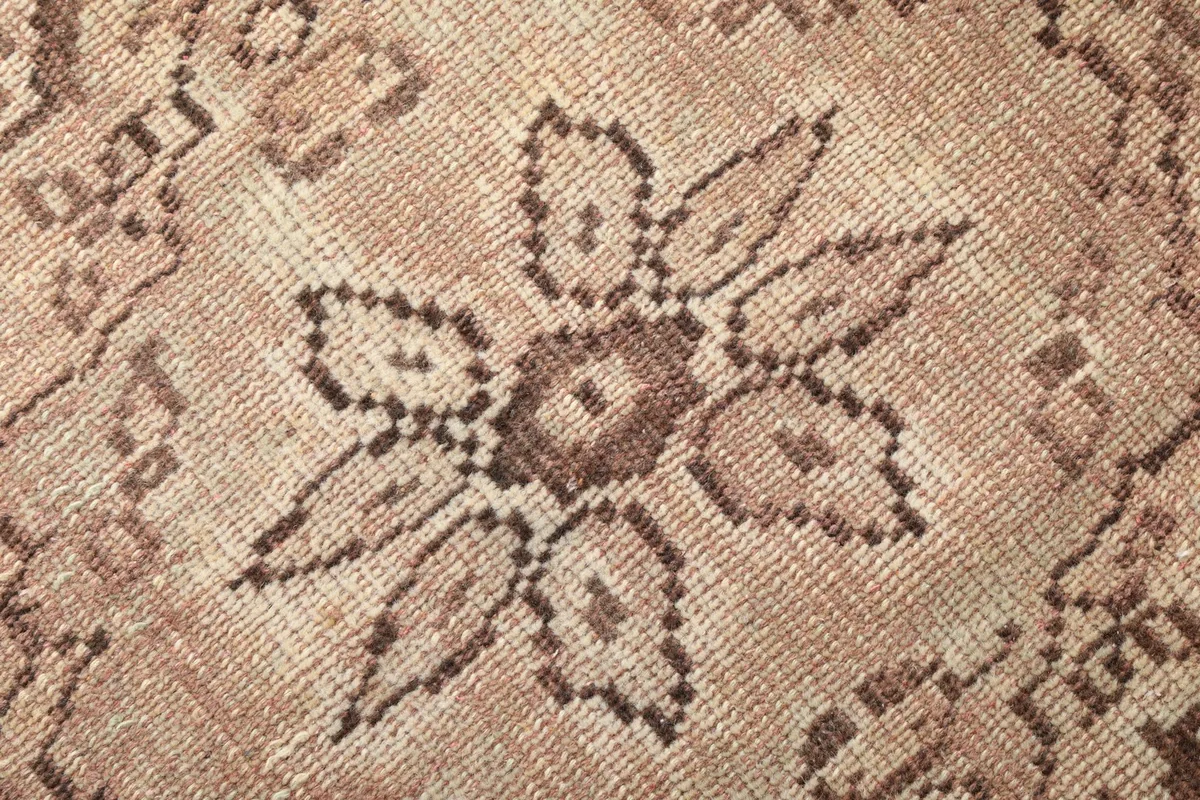 Close-up of the hand-knotted wool pile, showing the texture and detail of the brown floral motif.