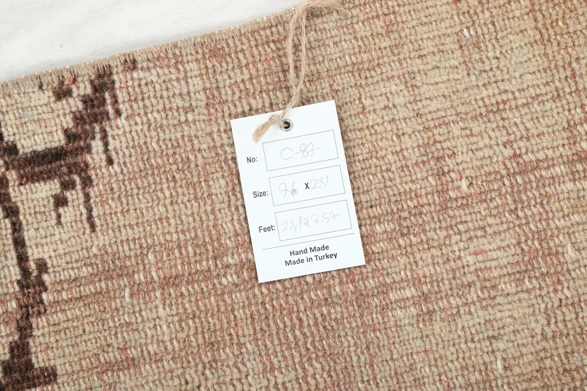 Detail of the rug with a product tag, indicating its handmade origin and dimensions.