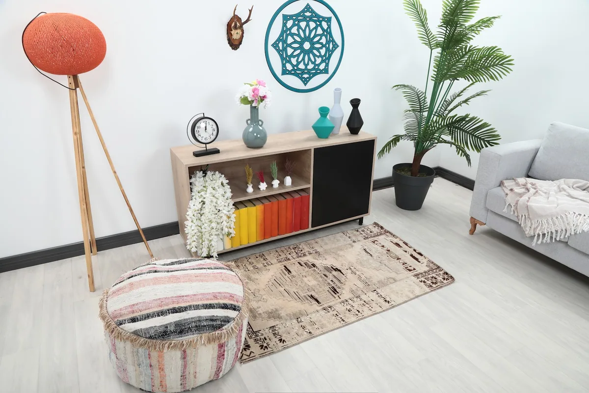 Vintage beige and charcoal rug placed in a modern living room setting with a light gray sofa and wooden cabinet