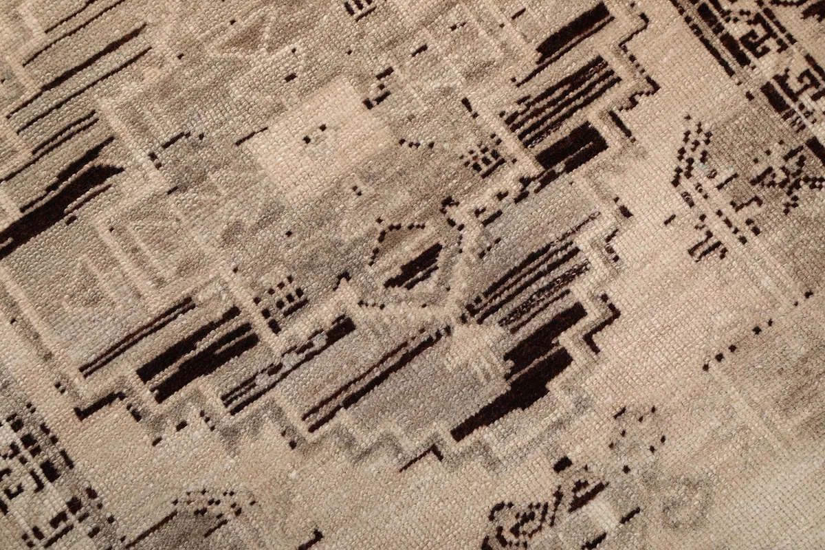 Close-up detail of the hand-knotted wool pile, showing the intricate charcoal and beige geometric motifs