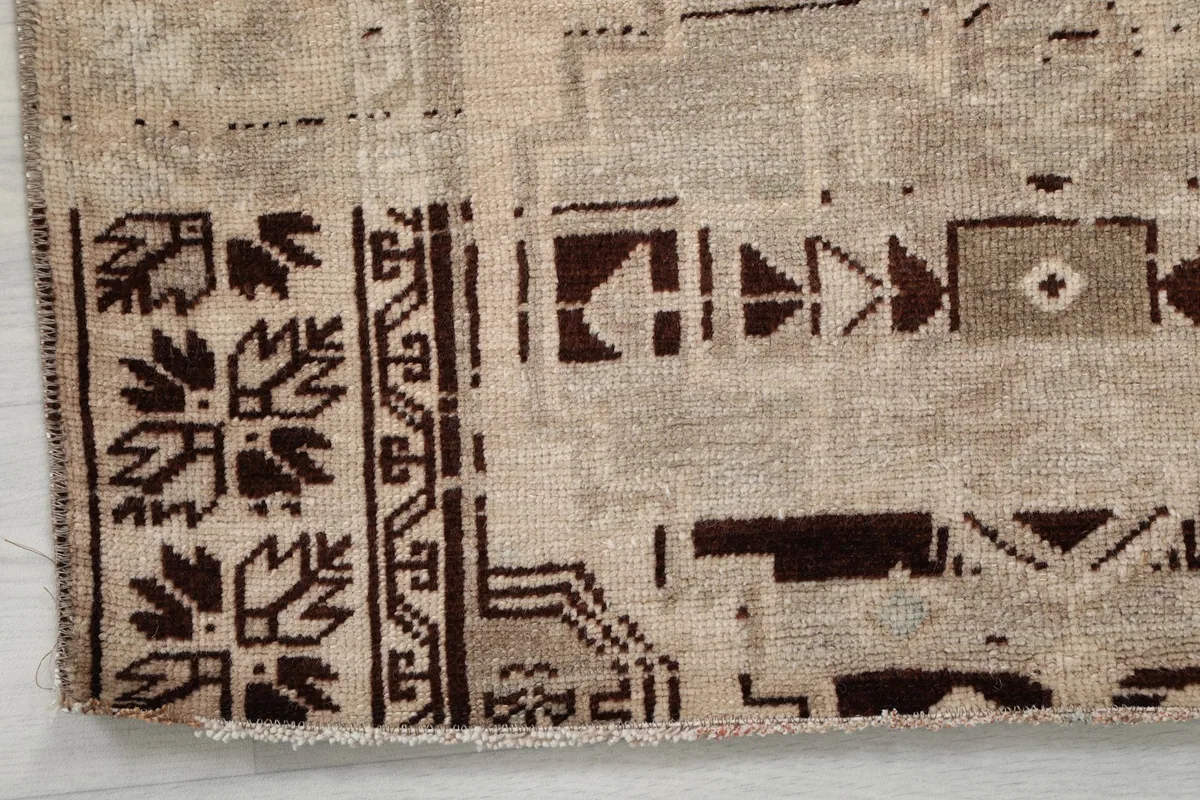 Detailed view of the rug's border design with tribal motifs in brown and charcoal