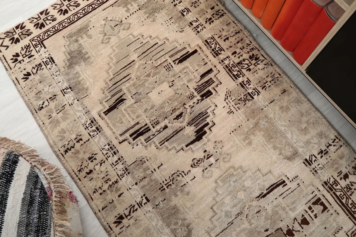 Overhead shot of the beige and charcoal rug, detailing the distressed geometric patterns and texture