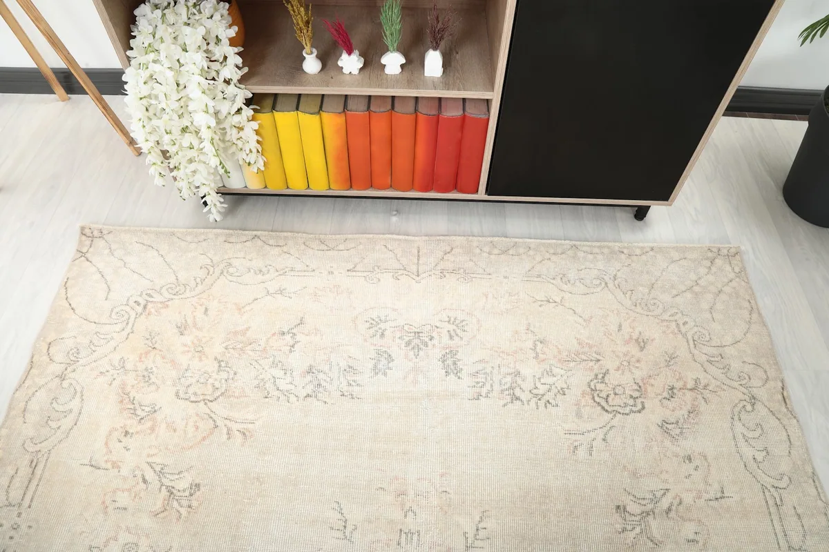 Detailed view of the rug's muted floral patterns and soft ivory tones from above.