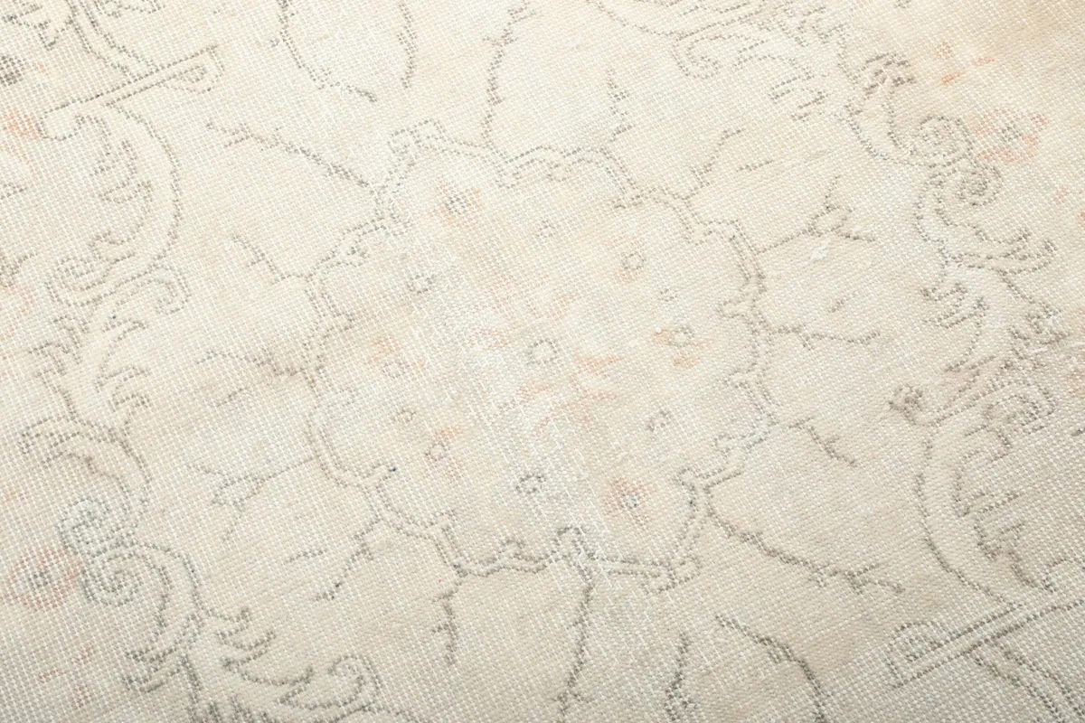 Close-up of the central medallion motif and surrounding floral details on the ivory rug.