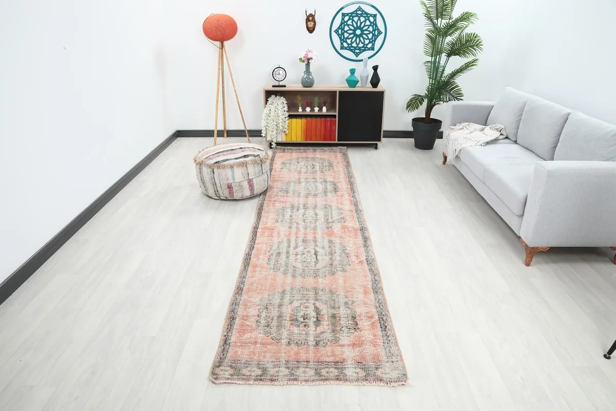 Vintage Anatolian runner rug with rose and gray colors in a modern hallway setting with a light sofa.
