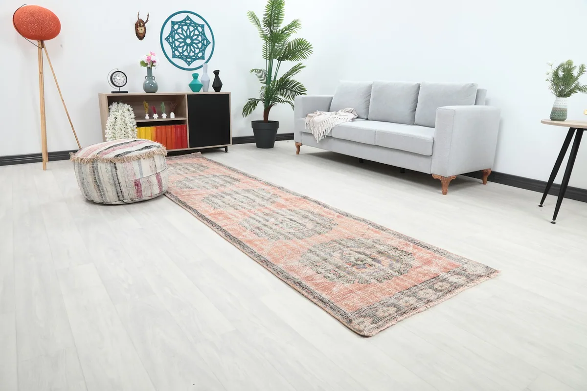 Angle view of the rose and gray medallion runner rug placed in a contemporary living space with minimalist furniture.