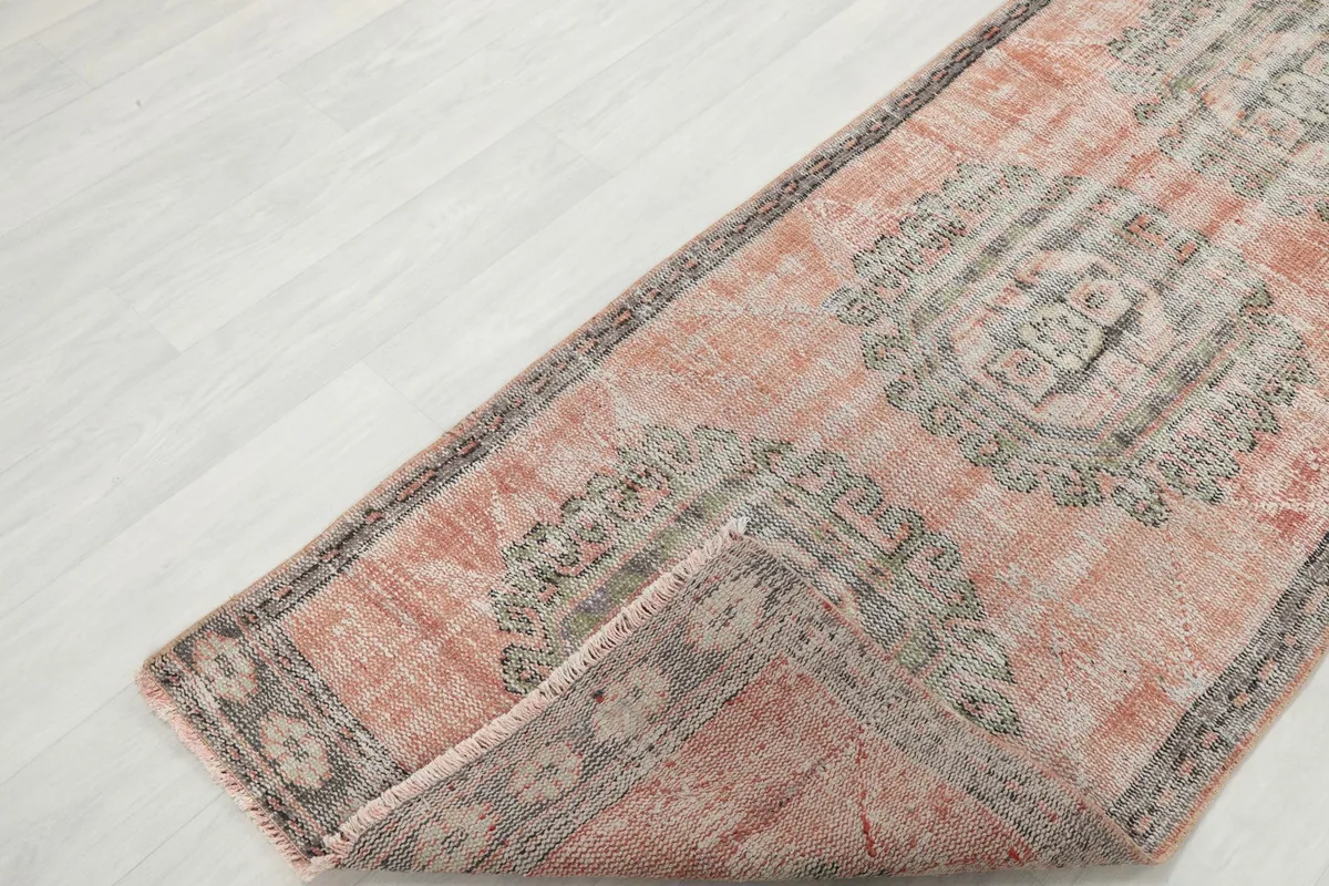 Folded corner of the runner rug, displaying the low pile and the construction of the hand-knotted wool on cotton foundation.