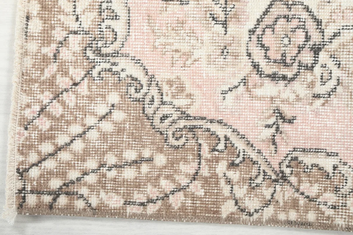 Extreme close-up of the rug's border design and fringe, showing the intricate patterns and wool fibers.