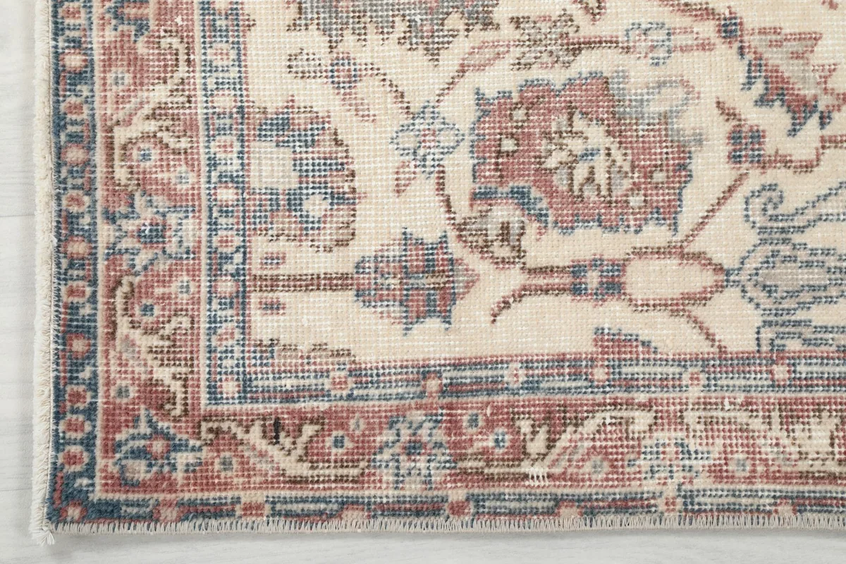 Corner detail of the rug's border, showcasing the rose and blue geometric and floral elements