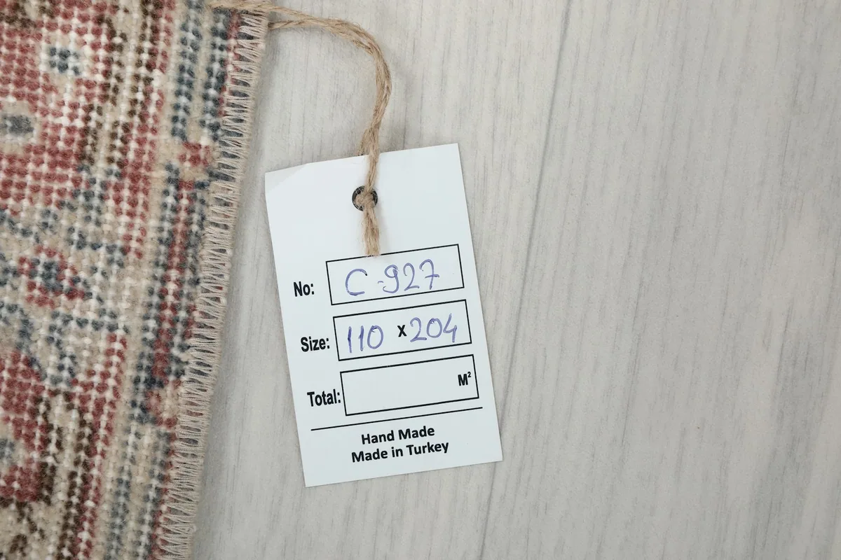 Product tag on the rug, displaying 'Hand Made Made in Turkey' and size '110 * 204' cm