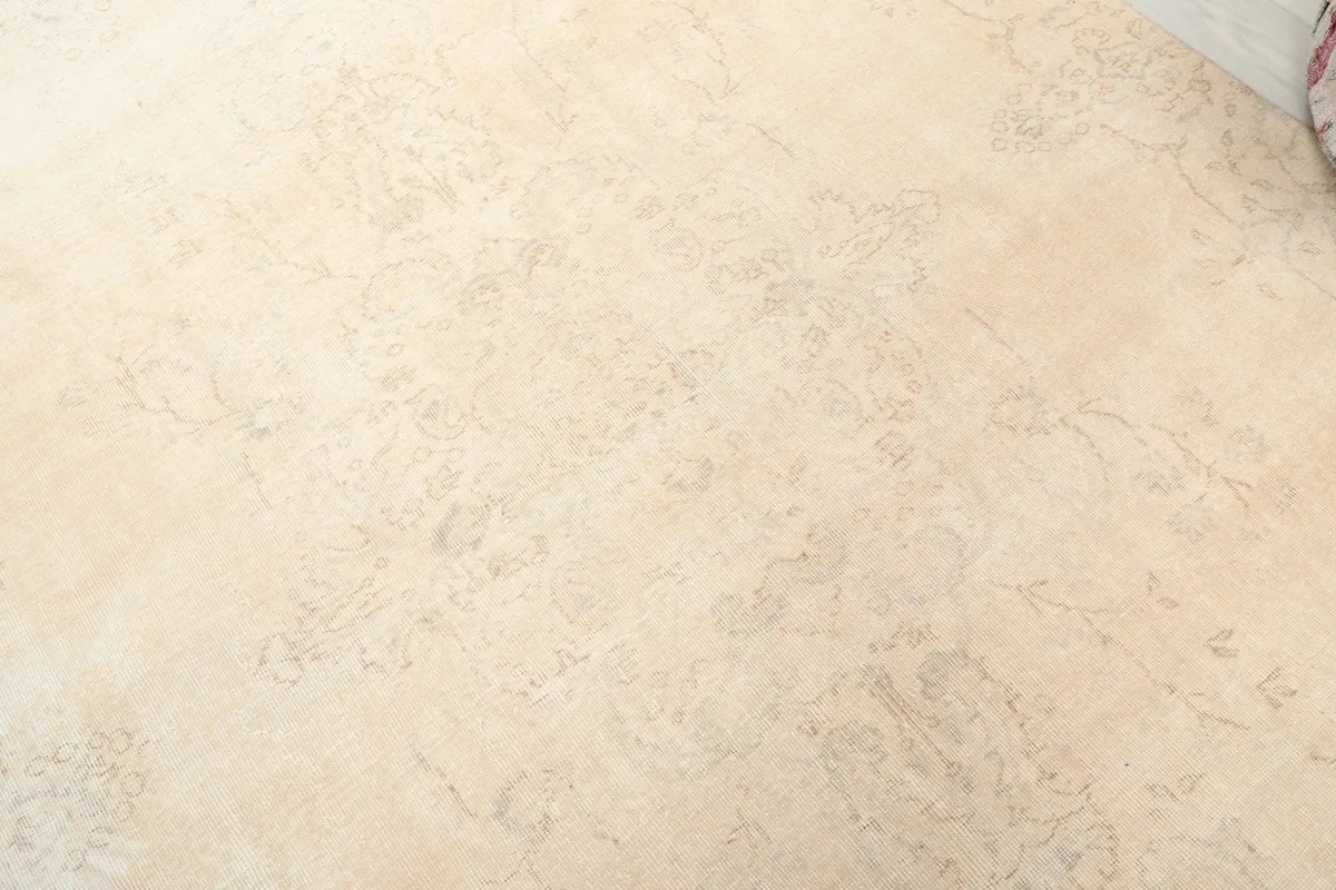 Detailed close-up of the faded floral and medallion patterns on the ivory rug