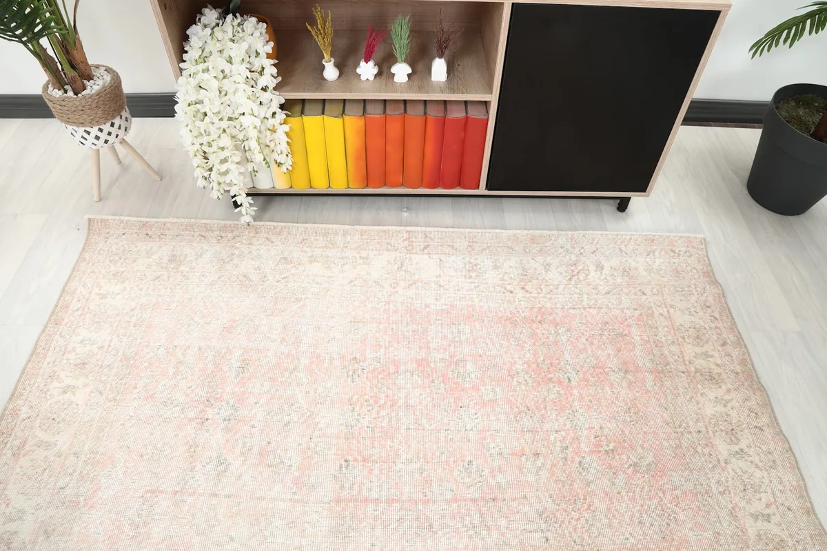 Top-down view of the rose and ivory rug in a room, highlighting its placement near a decorative cabinet.