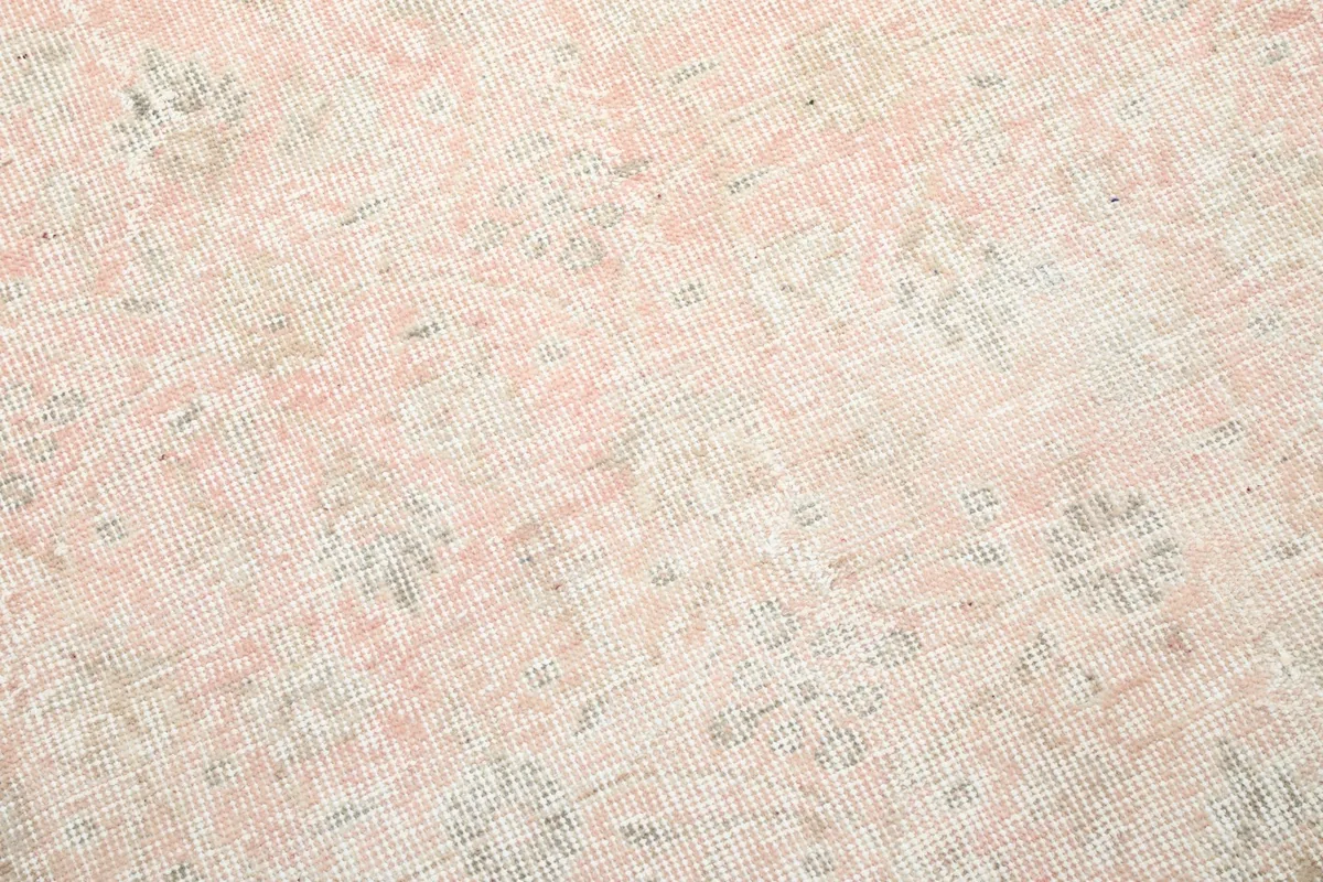 Close-up of the hand-knotted wool pile, showing the subtle rose and ivory color variations and pattern details.