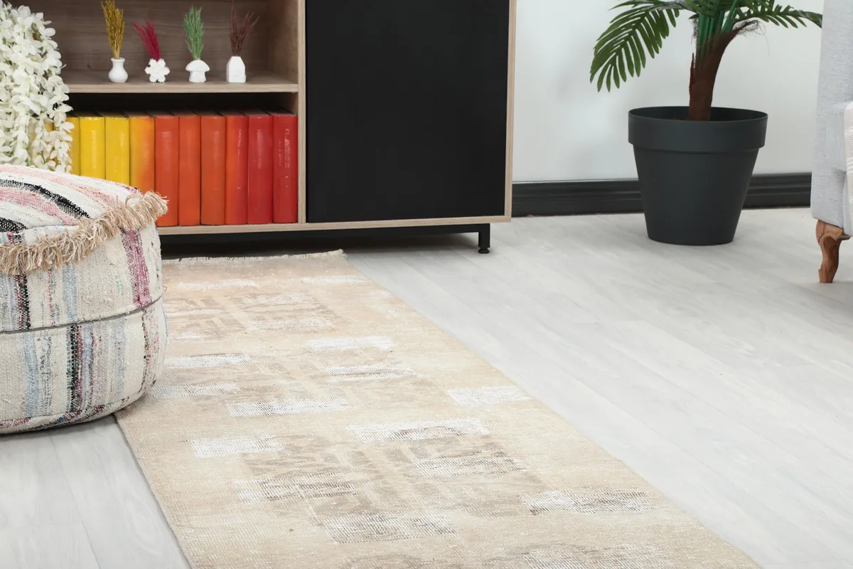 Close-up view of the runner rug in a room, showing its texture next to a decorative pouf.