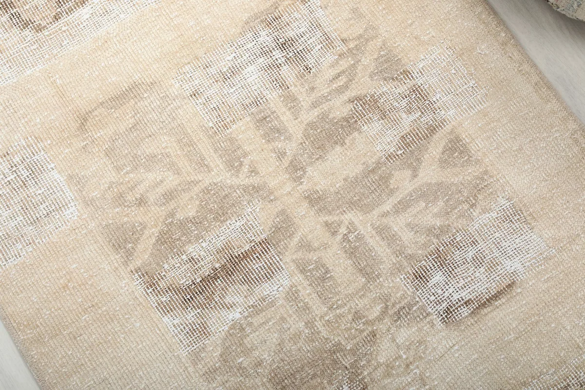 Close-up detail of the hand-knotted wool pile and geometric pattern, showing the vintage wear.