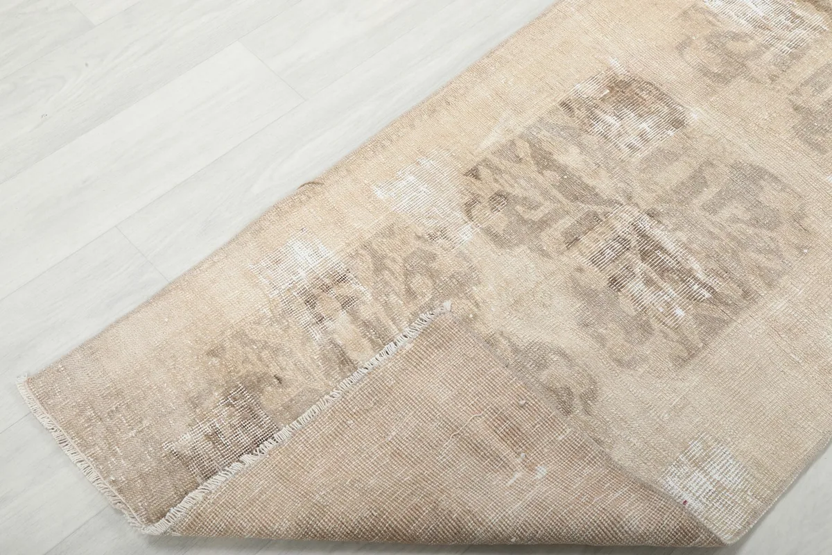 A corner of the runner rug folded back, displaying the wool pile and cotton foundation.