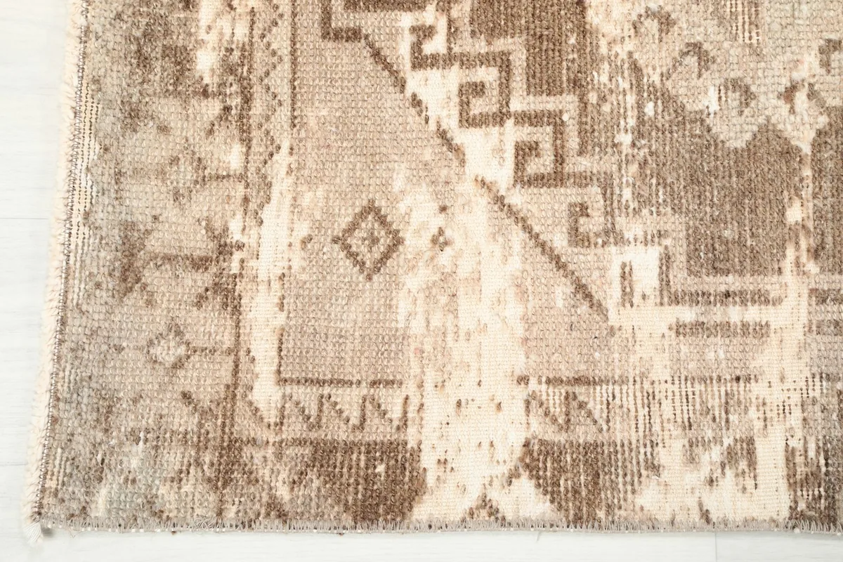 Detail of the distressed areas and natural patina on the rug's surface, revealing the cotton foundation