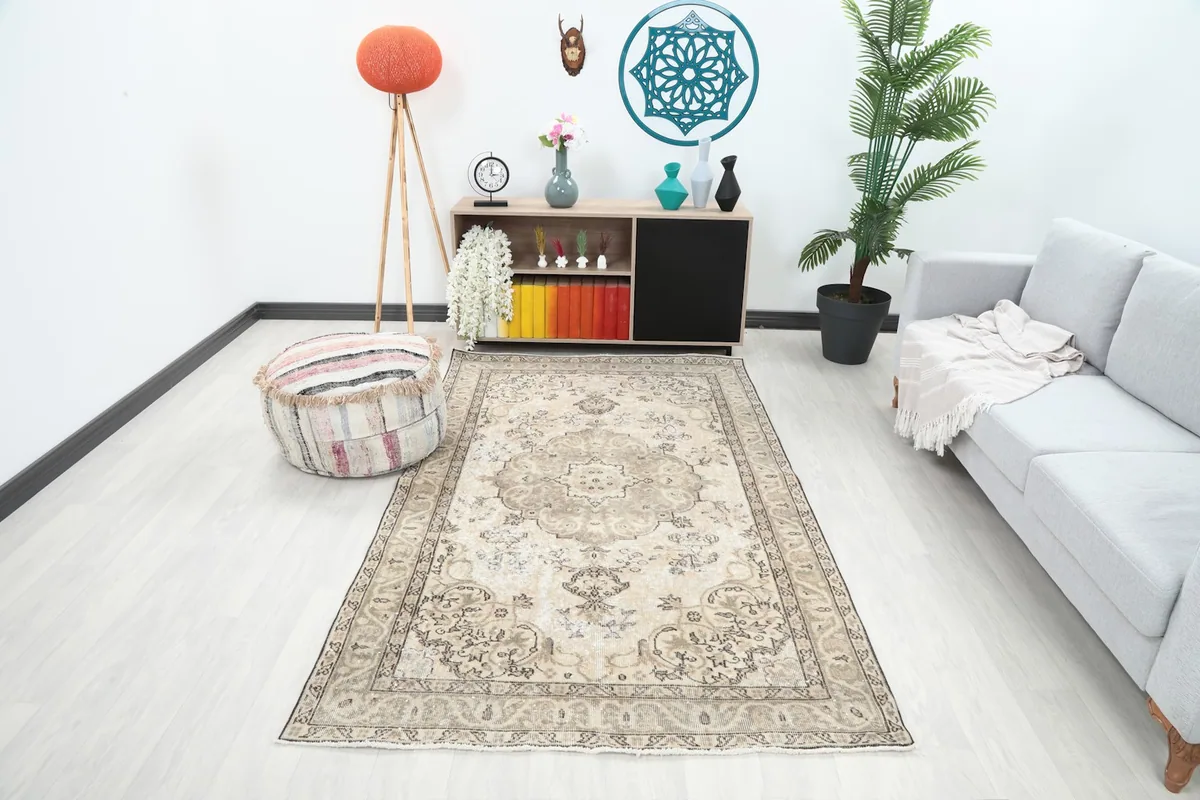 Vintage beige and brown Anatolian rug placed in a modern living room setting with a light gray sofa.