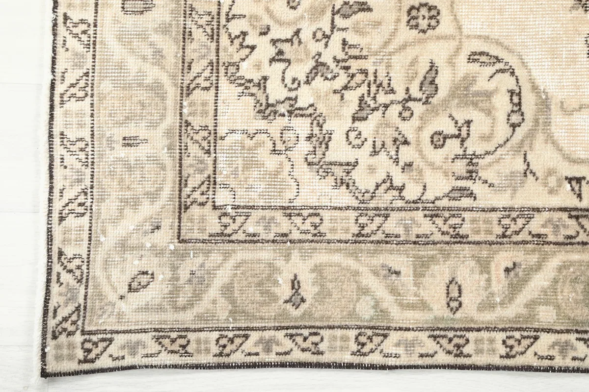 Corner detail of the rug's border, showcasing the distinct brown and gray patterns on a beige ground.
