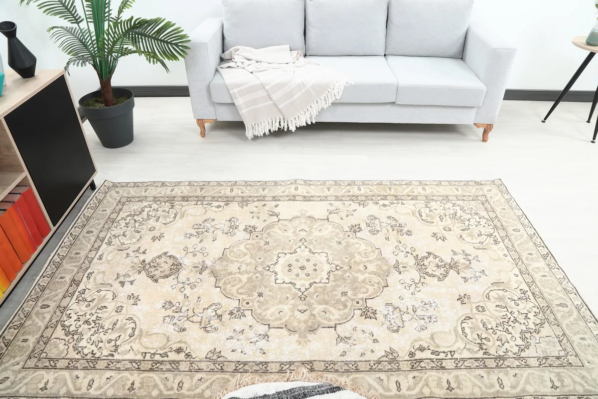 Overhead view of the beige and brown vintage rug in a room, highlighting its medallion and floral patterns.
