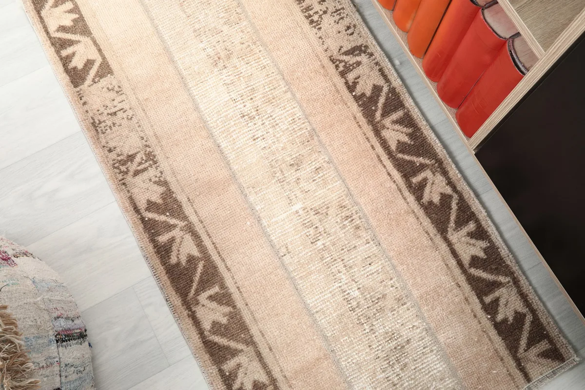 Diagonal view across the vintage rug, showing the variations in its tan color and texture.