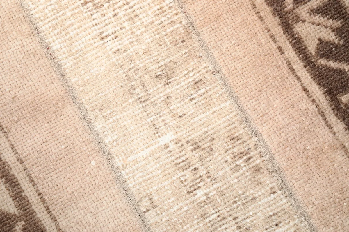Close-up of the rug's central tan panel, revealing the subtle variations in the wool pile.