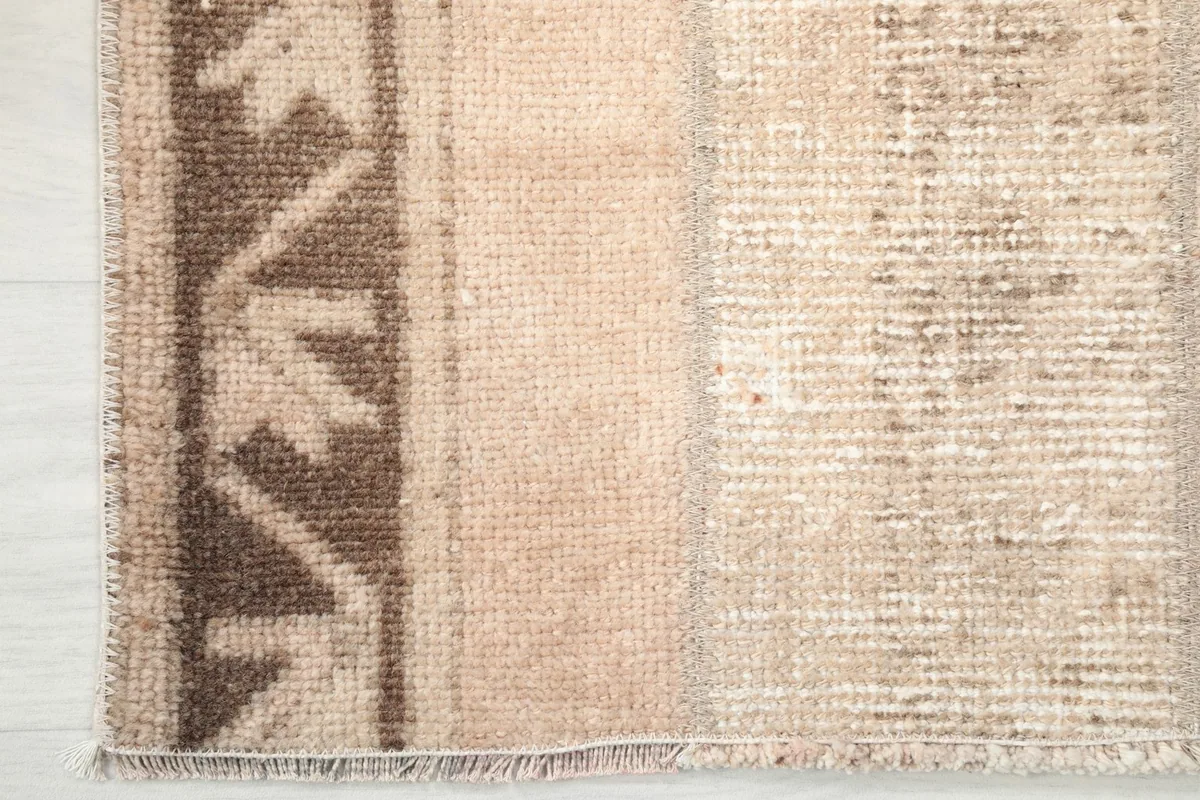 Detail of the rug's corner, showing the brown tribal border pattern and short fringe.